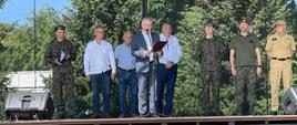 Wojewoda pomorski czyta list za nim stoją przedstawiciele wojska Państwowej Straży Pożarnej oraz władz samorządowych. 