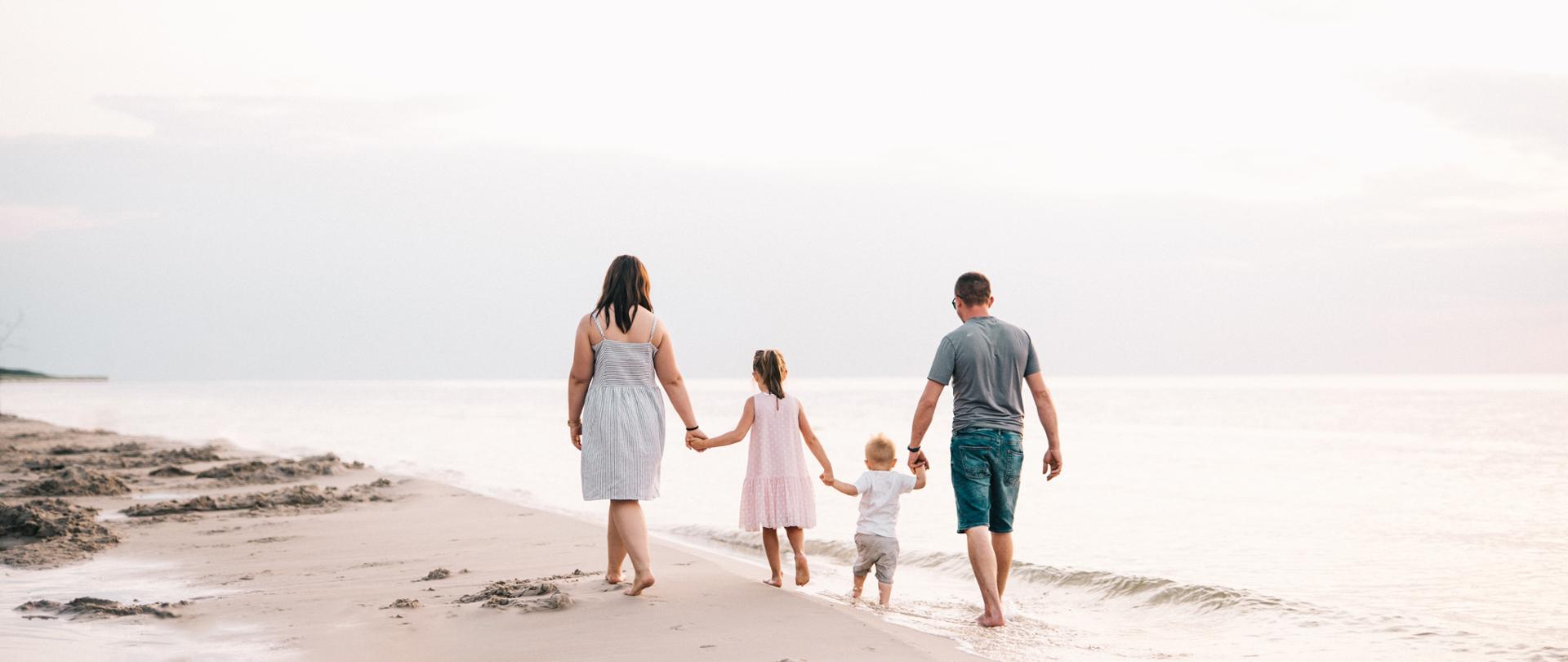 Spacerująca brzegiem morza rodzina