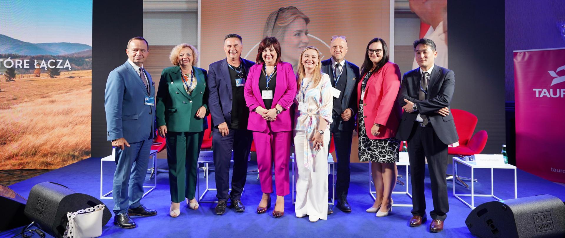 Grupa osób na scenie pozuje do zdjęcia