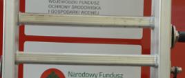 Nowy ciężki samochód ratowniczo-gaśniczy. Zdjęcie przedstawia fragment tylnej części samochodu pożarniczego. Naklejone na niej są logo Narodowego Funduszu Ochrony Środowiska i Gospodarki Wodnej, Wojewódzkiego Funduszu Ochrony Środowiska i Gospodarki Wodnej w Poznaniu. 