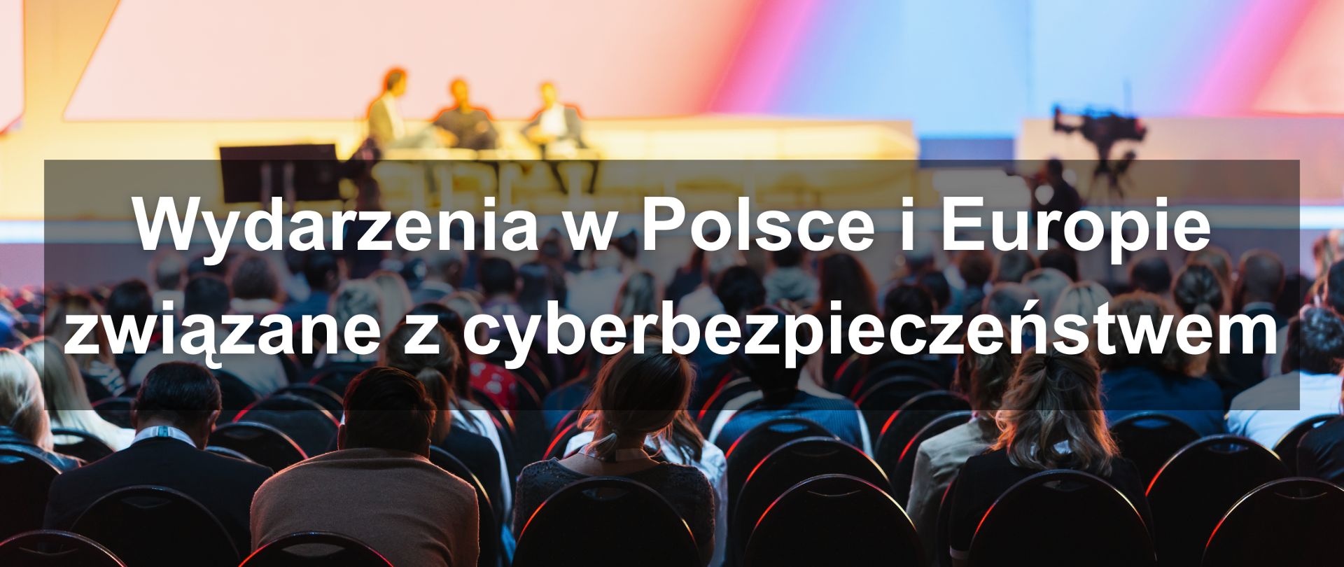 Uczestnicy konferencji słuchają panelu dyskusyjnego na scenie, na zdjęciu napis "Wydarzenia w Polsce i Europie związane z cyberbezpieczeństwem"