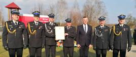 Druhowie OSP na wspólnym zdjęciu z oficerami PSP oraz zaproszonym gościem w ubraniu cywilnym, druhowie w dłoni prezentują decyzję o włączeniu jednostki do KSRG