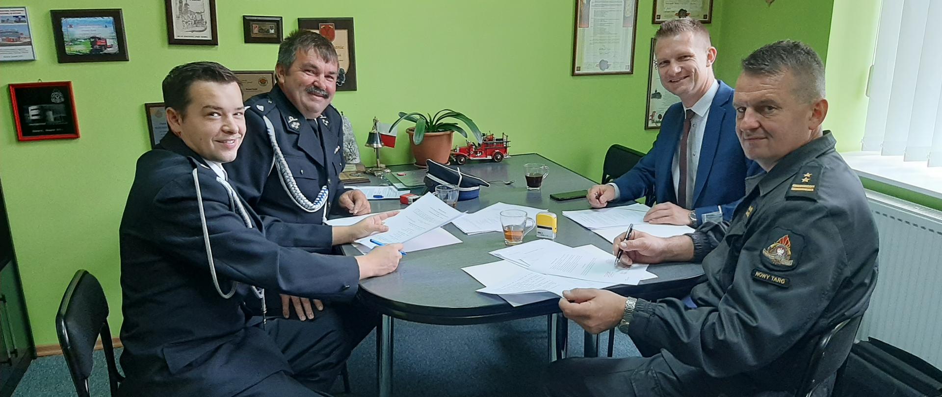 w gabinecie komendant przy stole siedzą wójt gminy komendant naczelnik i prezes