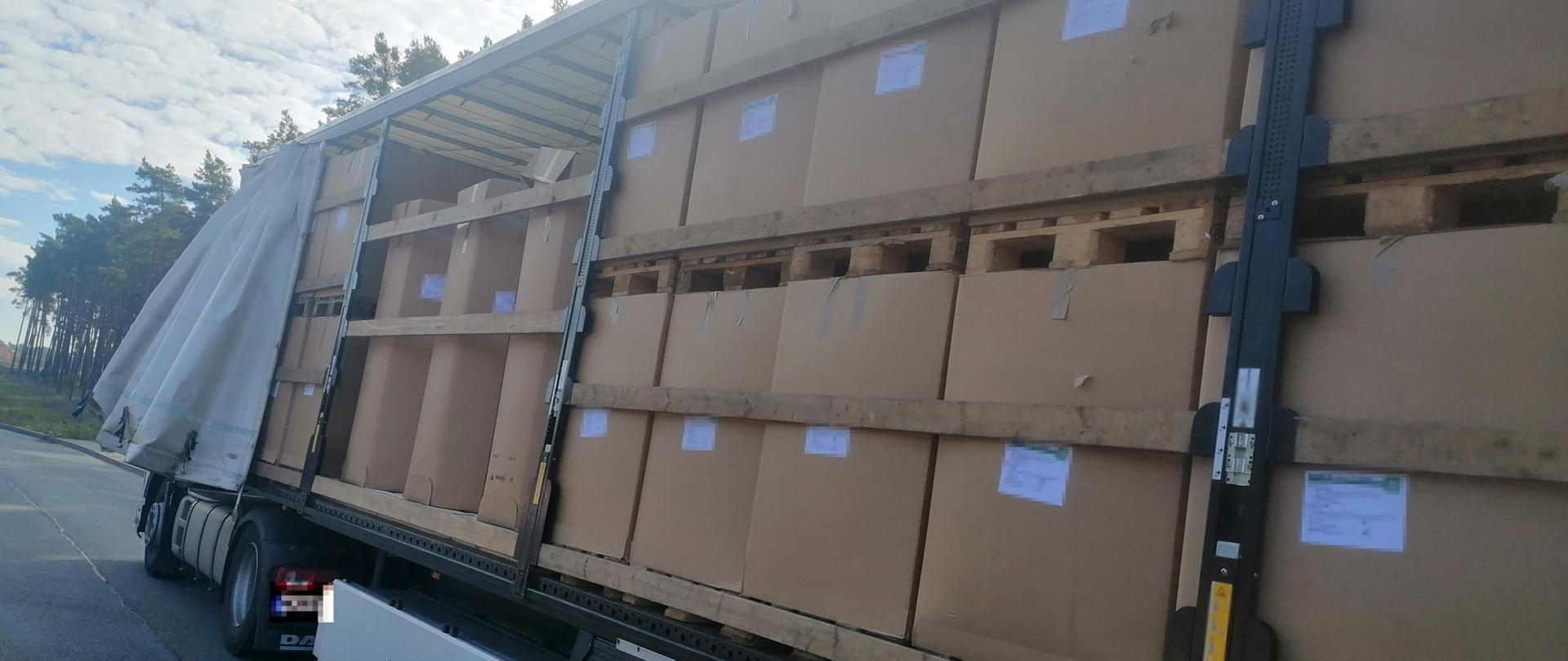 Bok otwartej naczepy samochodu ciężarowego, w środku kartony.