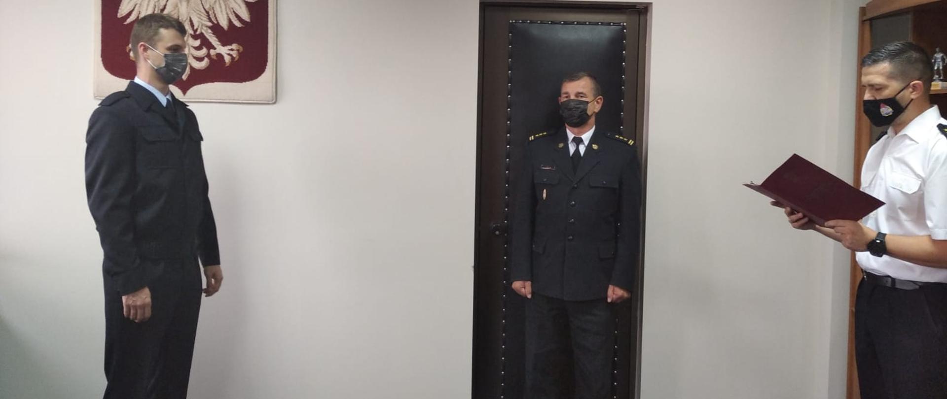 Z lewej strony strażak ślubujący Marcin Sobiesiak, w środku starszy brygadier Janisław Buller, z prawej starszy kapitan Marcin Zwolenkiewicz odczytujący rotę ślubowania.