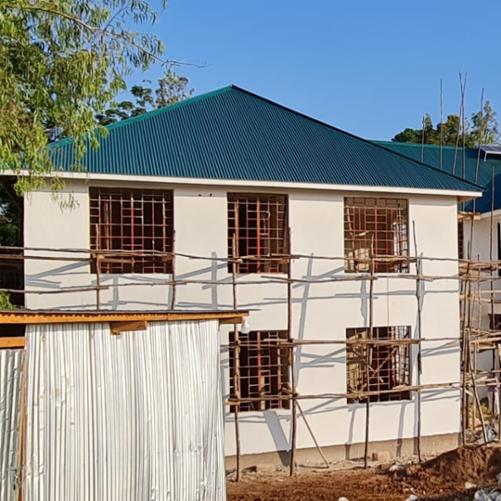 Otynkowany budynek z zielonym dachem.