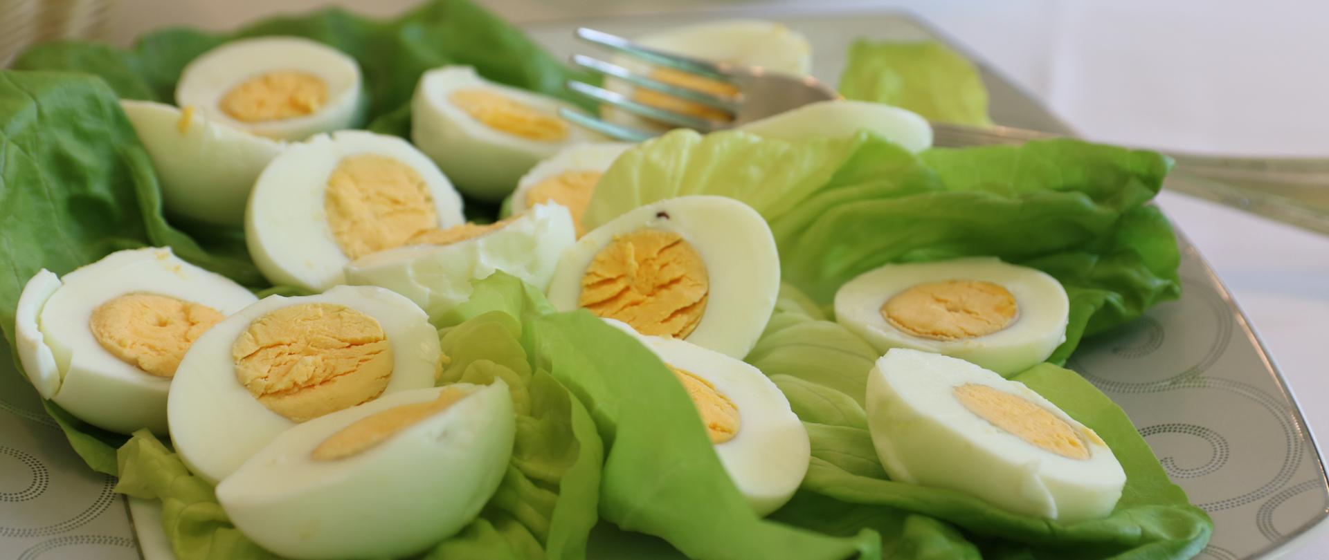 Przekrojone na pół jajka na liściach sałaty