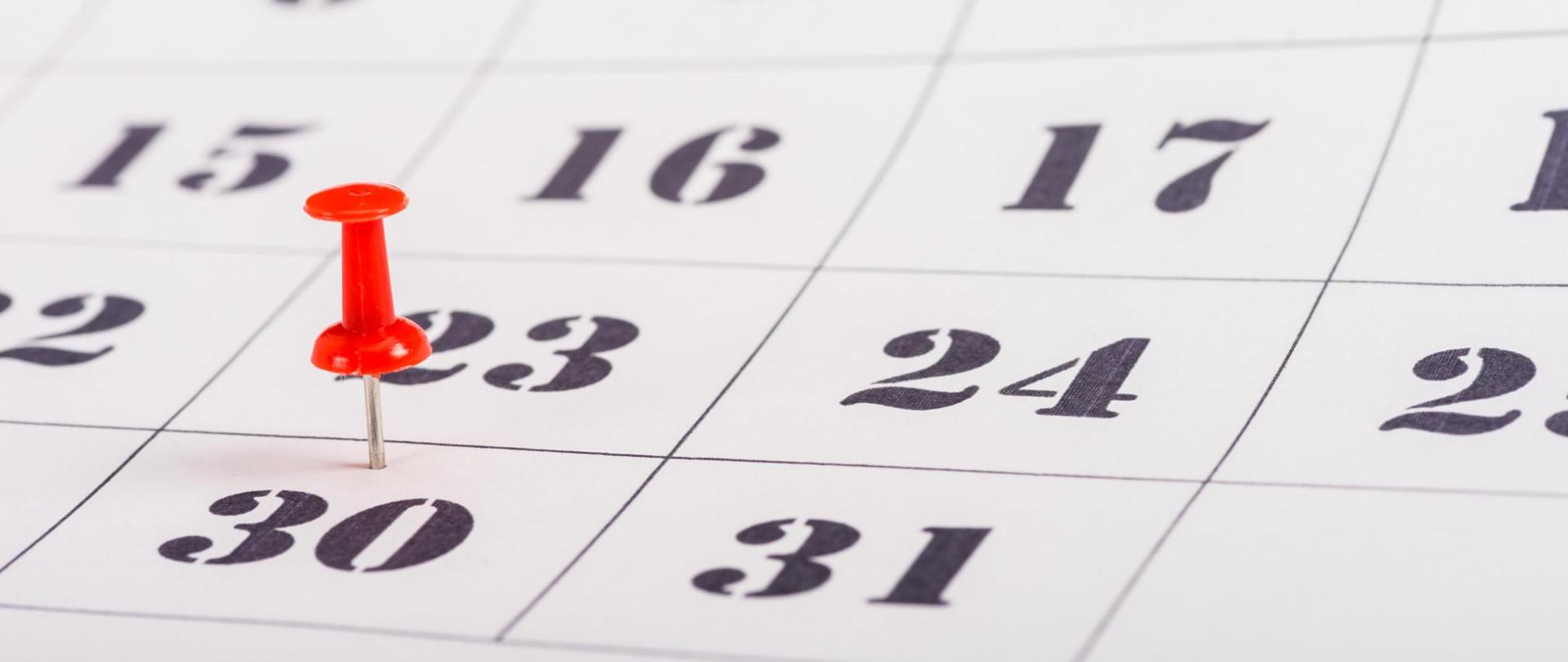 Na zdjęciu jest kartka z kalendarza, na 30-stym dniu jest wbita czerwona szpilka.