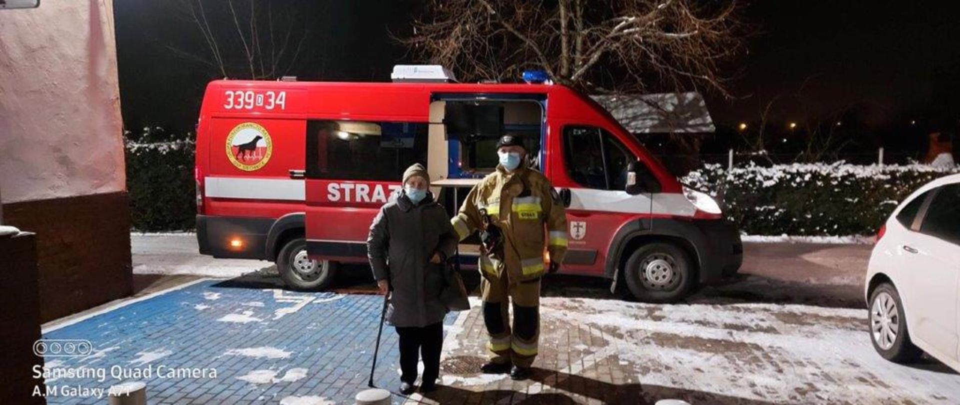 Na zdjęciu strażak prowadzi kobietę do punktu szczepień 