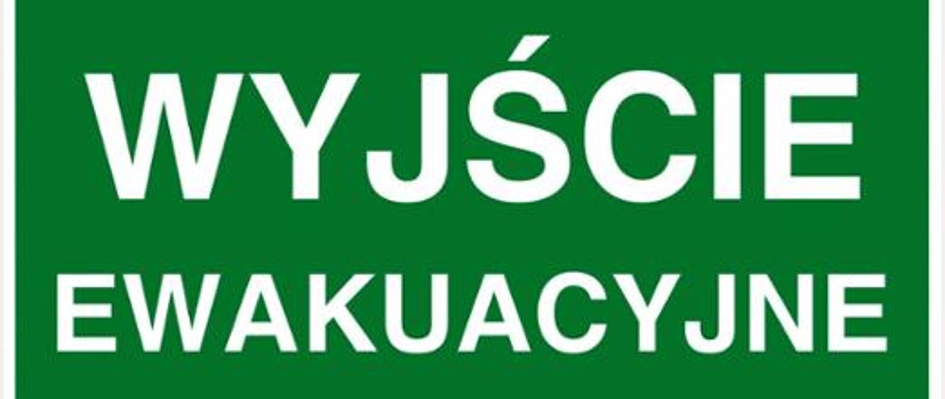Zdjęcie przedstawia tablicę informacyjną wskazującą na wyjście ewakuacyjne. Tablica zawiera zielone tło fluorescencyjne na którym widnieje napis "wyjście ewakuacyjne"