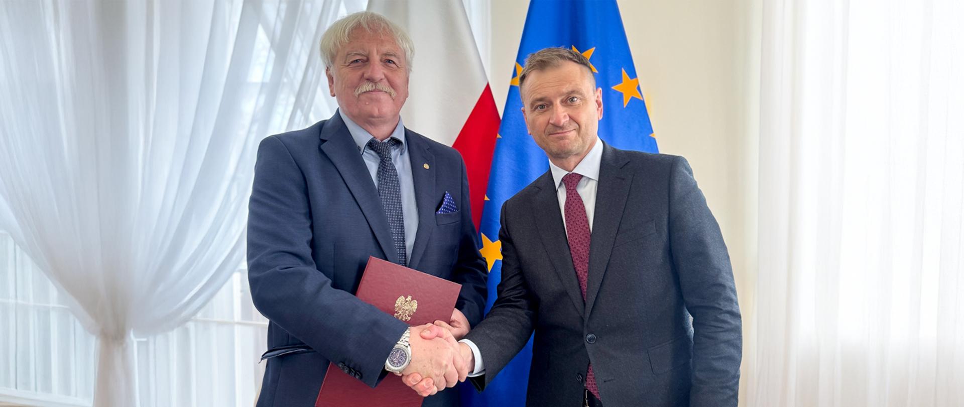 Jerzy Eliasz z Ministrem Sportu i Turystyki Sławomirem Nitrasem na tle flagi Polski i Unii Europejskiej