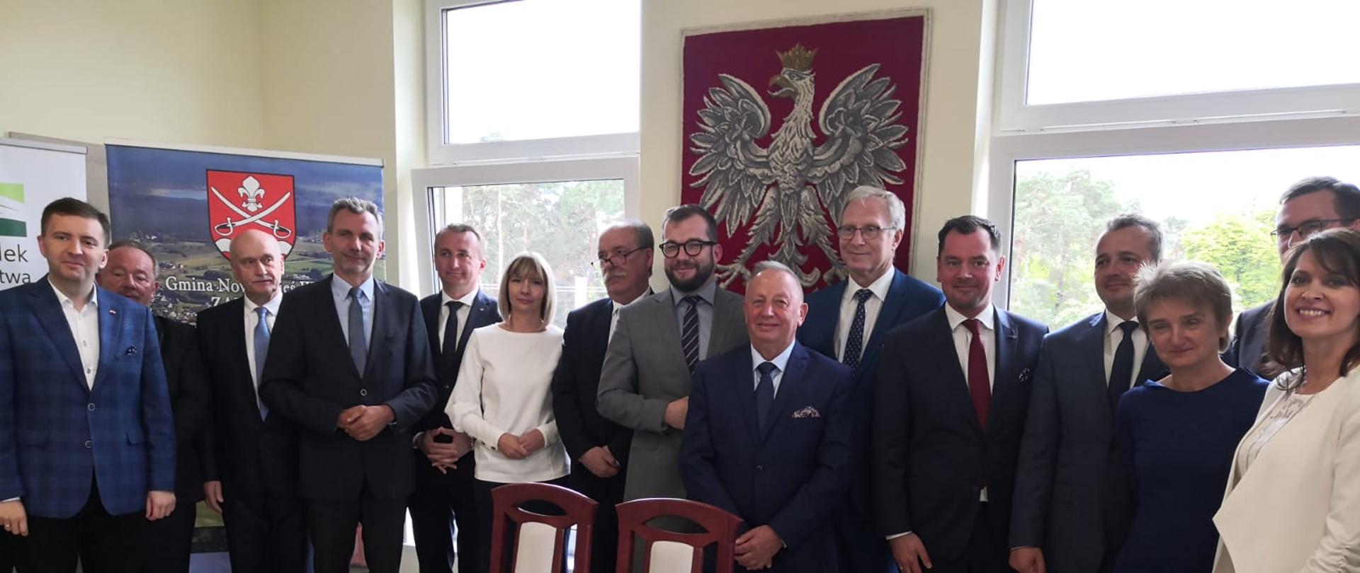 Grupa osób stojących za stołem, wśród nich minister Grzegorz Puda.