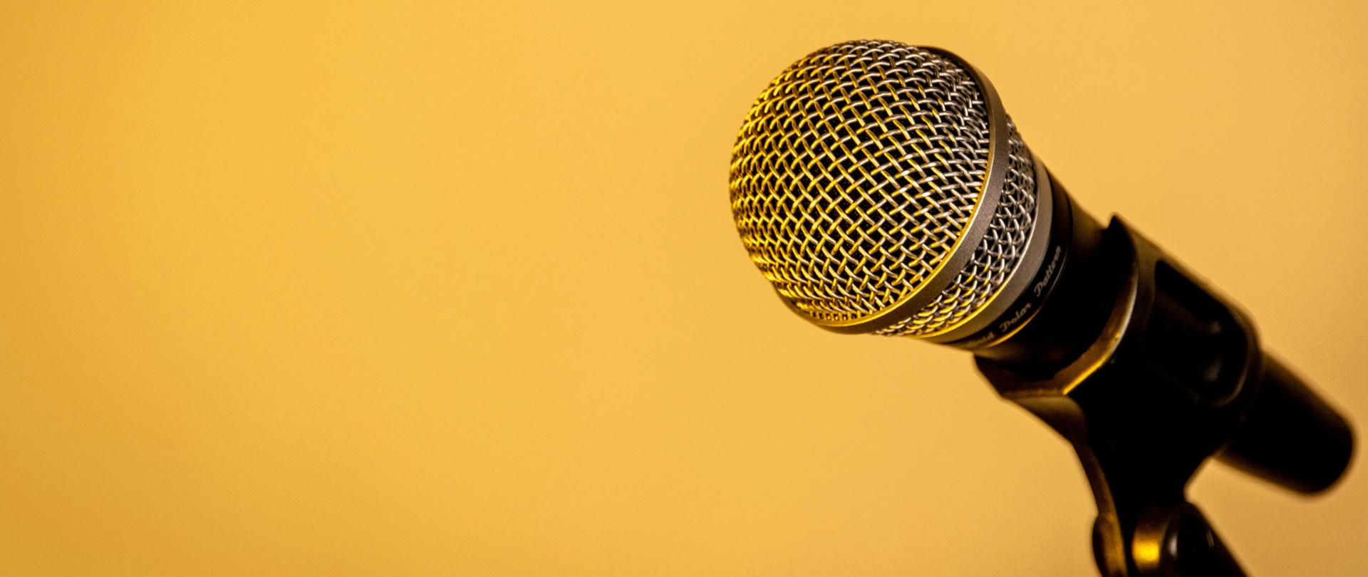 Mikrofon zaczepiony na statywie na żółtym tle