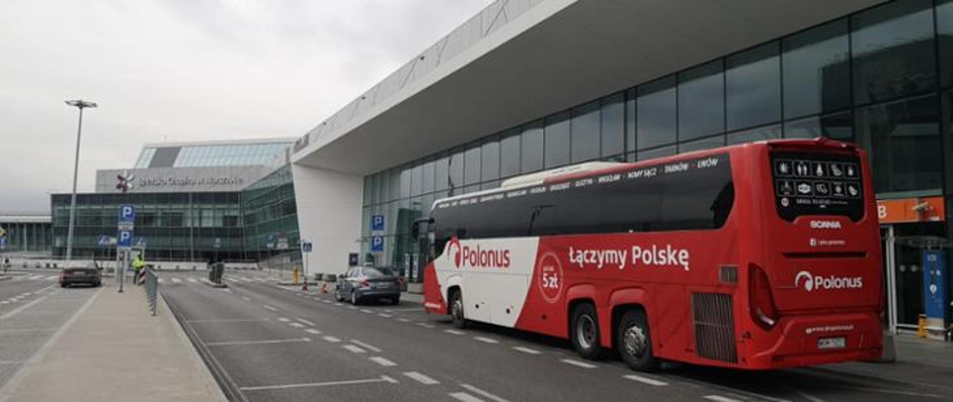 Czerwony autobus firmy Polonus zaparkowany na Lotnisku Chopina w Warszawie. 