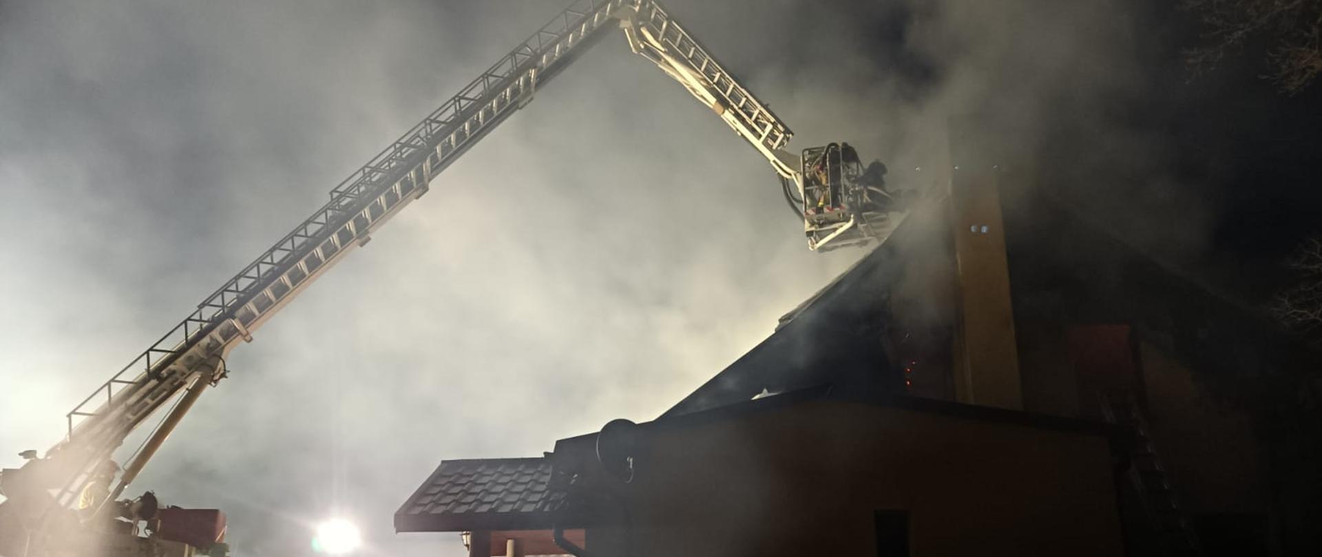 Strażacy gaszą pożar domu z podnośnika