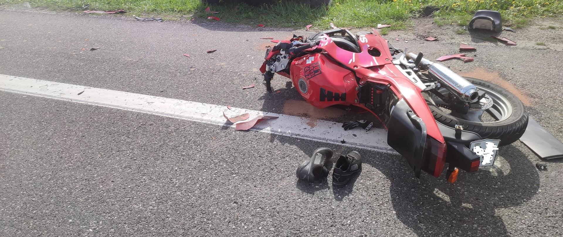 Zdjęcie przedstawia motocykl na jezdni, w tle samochód osobowy.