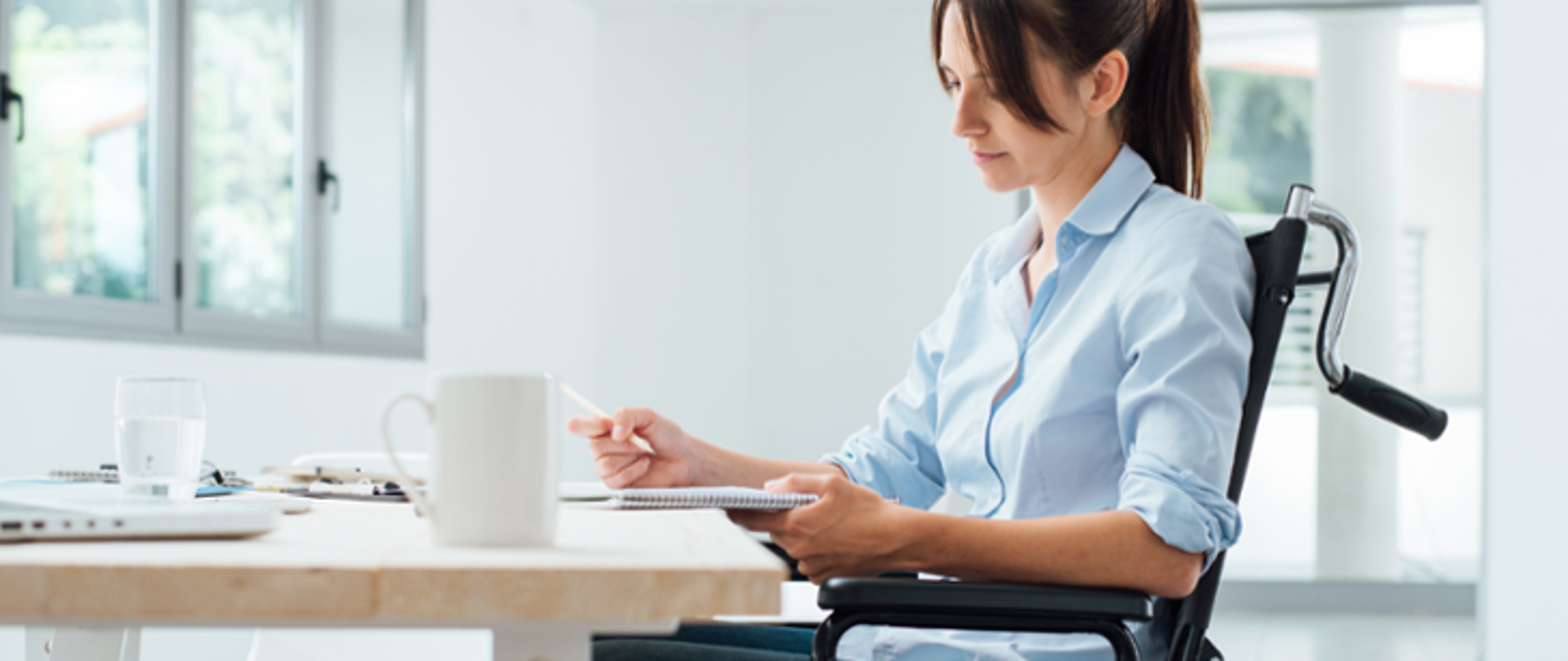kobieta z niepełnosprawnością siedząca przy biurku 