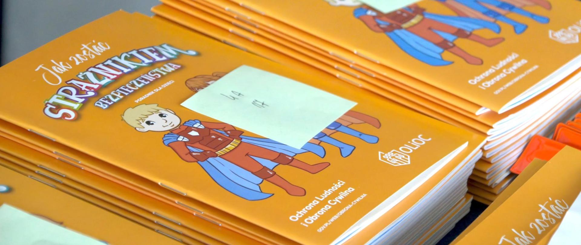 Na zdjęciu poradniki bezpieczeństwa dla dzieci z grafiką i opisem Jak zostać strażnikiem bezpieczeństwa
