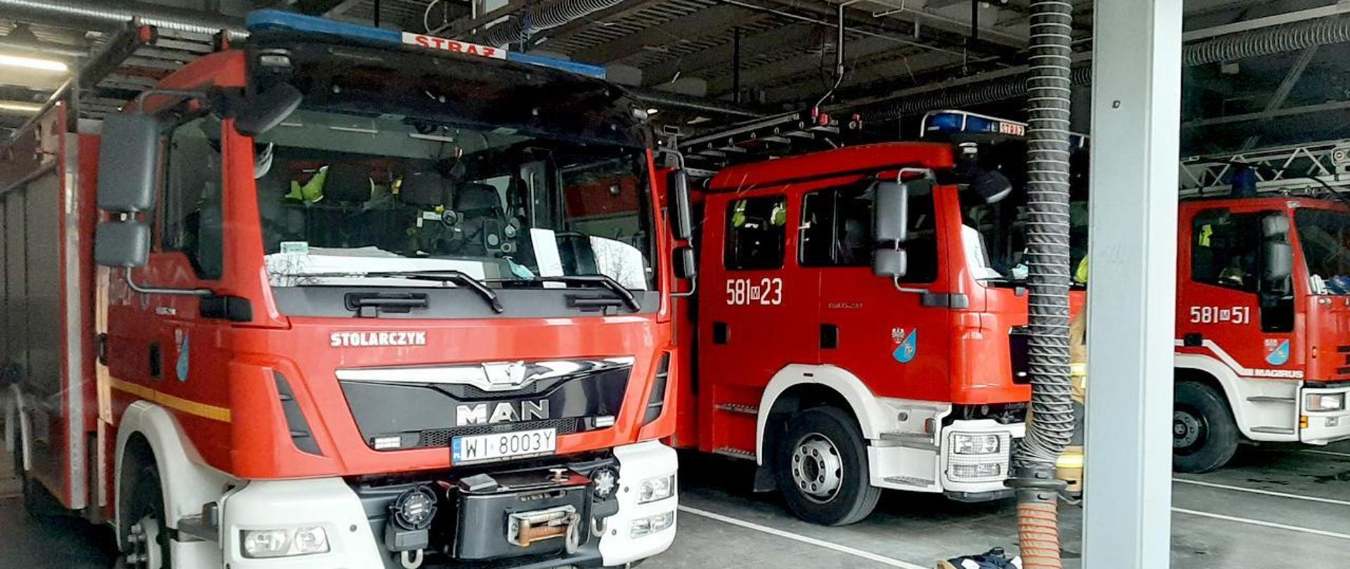 Zdjęcie przedstawia wnętrze garażu JRG Pruszków. Na głównym planie widać trzy samochody ratowniczo-gaśnicze. 