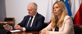 Od lewej, za stołem konferencyjnym, siedzą Jarosław Gowin i Anna Kornecka. Za nimi flagi polska i unijna, przed nimi notatki i mikrofon.