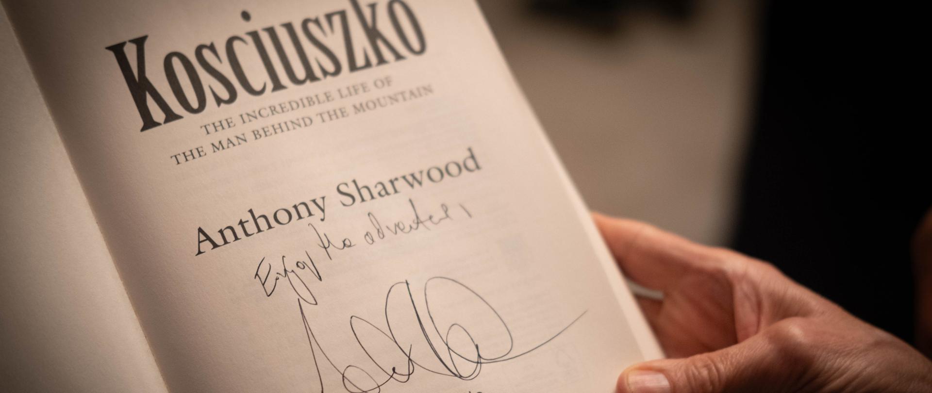 Ksiażka"Kosciuszko: The incredible life of the man behind the mountain" trzymana w rękach i otwarta na pierwszej stronie z autografem autora.
