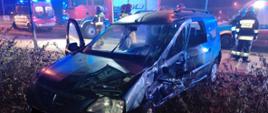 Dacia Logan z uszkodzeniami po wypadku, w tle widać strażaków, karetkę oraz wozy bojowe