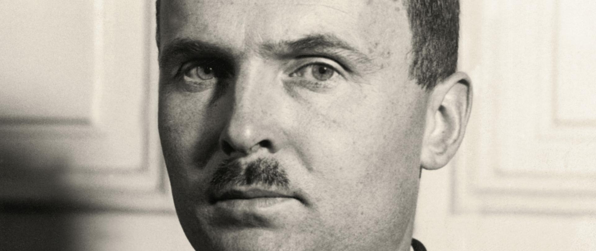 Adam Tarnowski - portret mężczyzny z drobnym wąsem, ciemne włosy, ciemna marynarka, ciemny krawat, biała koszula.