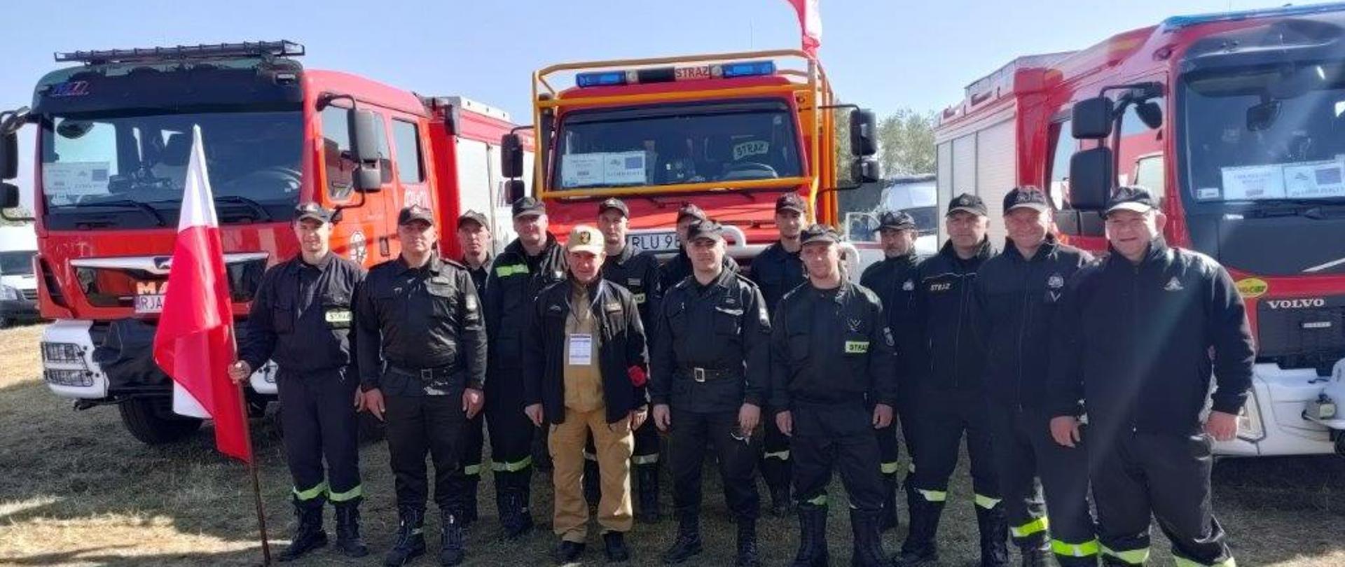 Na zdjęciu widać strażaków podkarpackiej brygady, na czele z zastępcą komendanta wojewódzkiego PSP st. bryg. Andrzejem Marczenią, któzy pozują do zdjęcia grupowego. Jeden ze strażaków trzyma w ręku flagę Polski. W tle widać samochody pożarnicze.