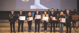 Wyróżnieni goście stoją w szeregu i trzymają podziękowania.
