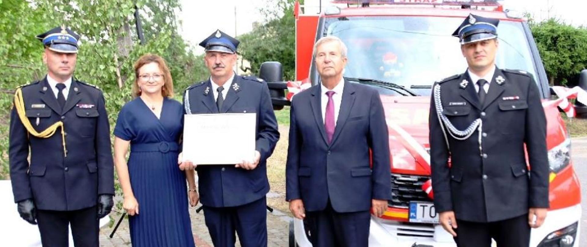 Akt przekazania w rękach prezesa jednostki w asyście zaproszonych gości. 