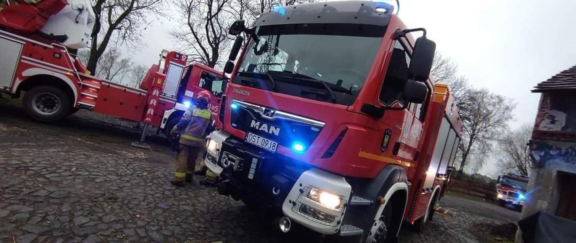 Na zdjęciu znajdują się samochody bojowe oraz strażak