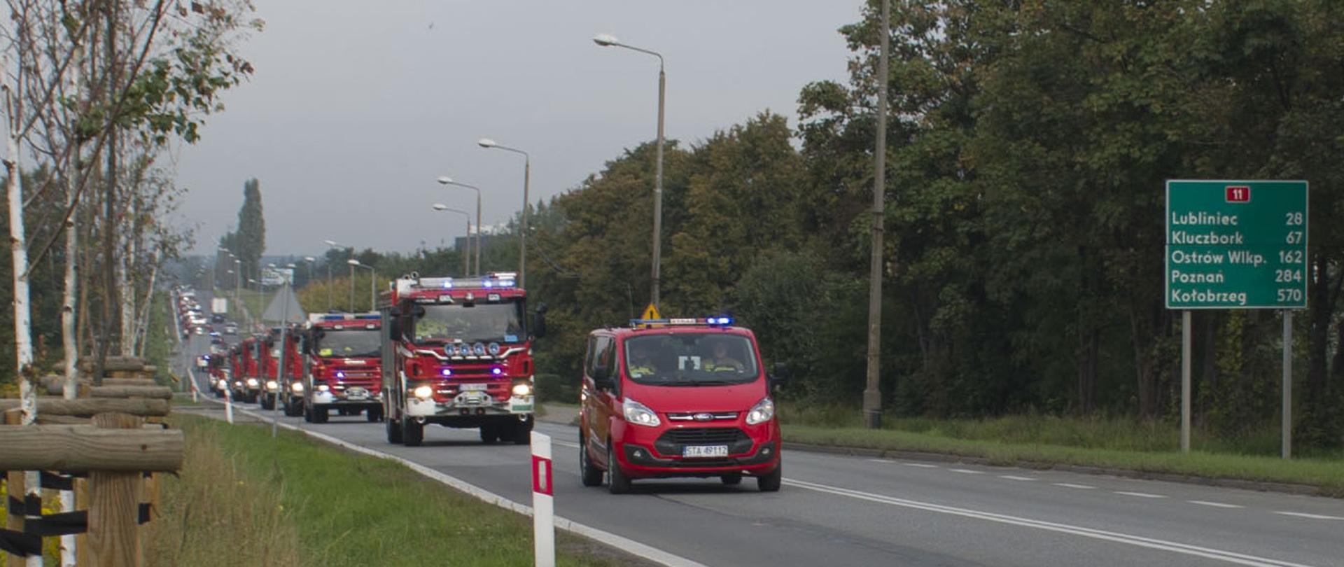 Pojazdy strażackie w kolumnie jadą po ulicy