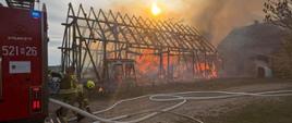 Paląca się stodoła oraz zastęp straży pożarnej podczas rozwinięcia bojowego.