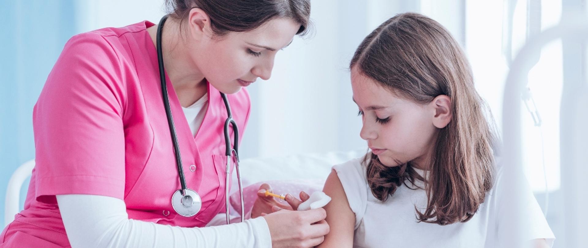 Zdjęcie przedstawia lekarza wykonującego szczepienie dziecku