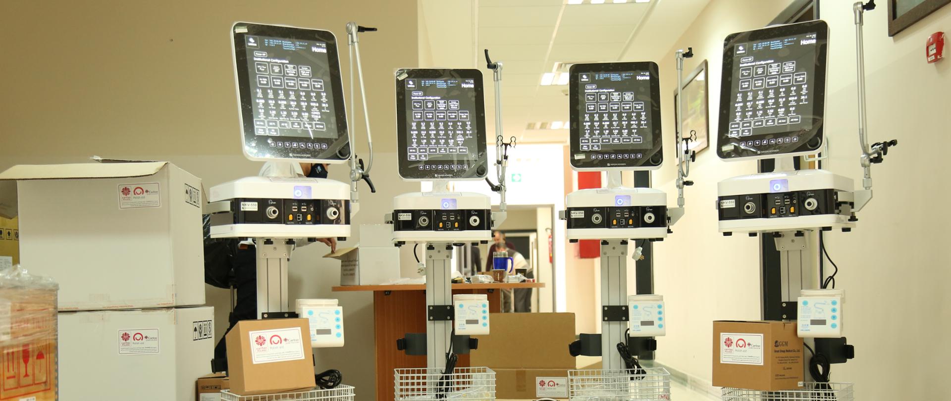 Cztery urządzenia medyczne z ekranami na kółkach