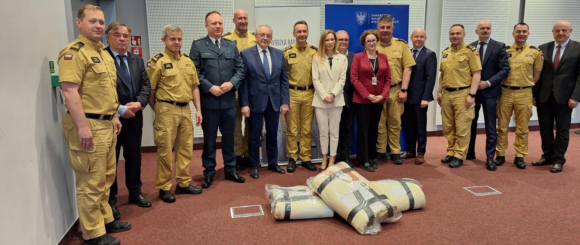 Strażacy i urzędnicy uczestniczą w przekazaniu płacht gaśniczych.