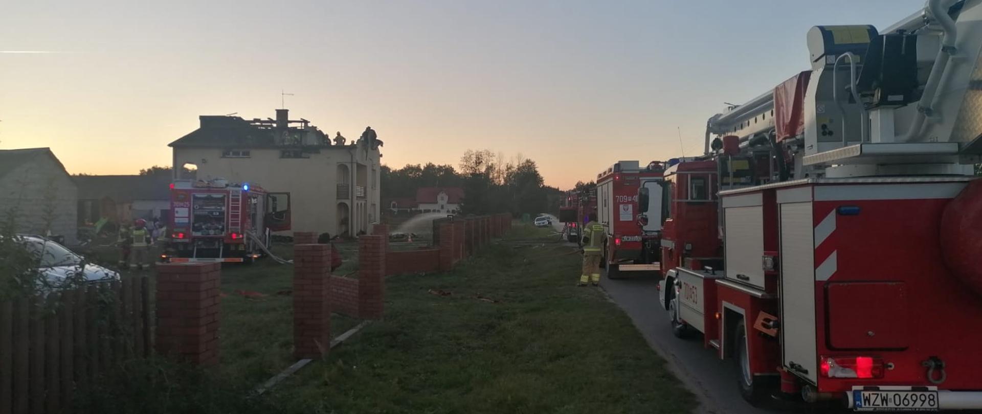 Wozy bojowe stojące na ulicy, w tle budynek ze spalonym poddaszem