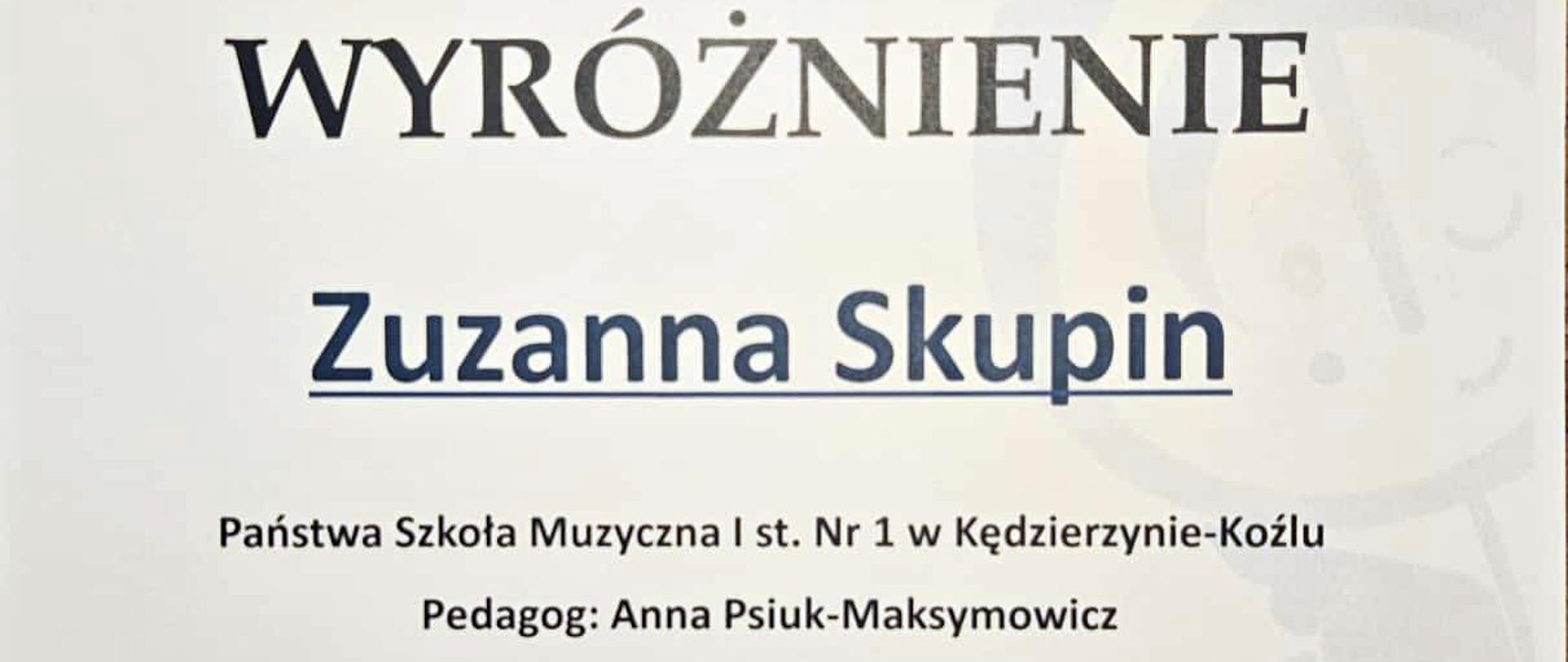 Na plakacie w jasnej, białej kolorystyce przedstawiono dyplom z niebieskimi i czarnymi elementami graficznymi, w tym logo z kluczem wiolinowym i stylizowaną postacią dziecka oraz falującym motywem muzycznym u dołu.
Centralnie dużą czcionką zapisano „WYRÓŻNIENIE”, poniżej imię i nazwisko „Zuzanna Skupin”, a wyżej informację o VI Ogólnopolskim Konkursie „Co Młodym w Duszy Gra?” z datą 23–25 kwietnia 2026 roku i miejscem wydarzenia.
W dolnej części znajdują się nazwa szkoły, nazwisko pedagoga, podpisy organizatorów i jury oraz rząd logotypów patronów i sponsorów.