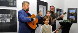 Czwórka osób trzymająca gitary na tle wystawy na wernisażu czeskiej fotografii w Kłodzkim Ośrodku Kultury - 16 grudnia 2023