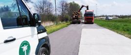 Kontrola inspektorów małopolskiej ITD, zakończona przeładowaniem nadmiaru ładunku. Na pierwszym planie inspekcyjny furgon. W centrum dwa pojazdy ciężarowe, jeden z nich mocno załadowany drewnem. Trwa przeładunek części ładunku.