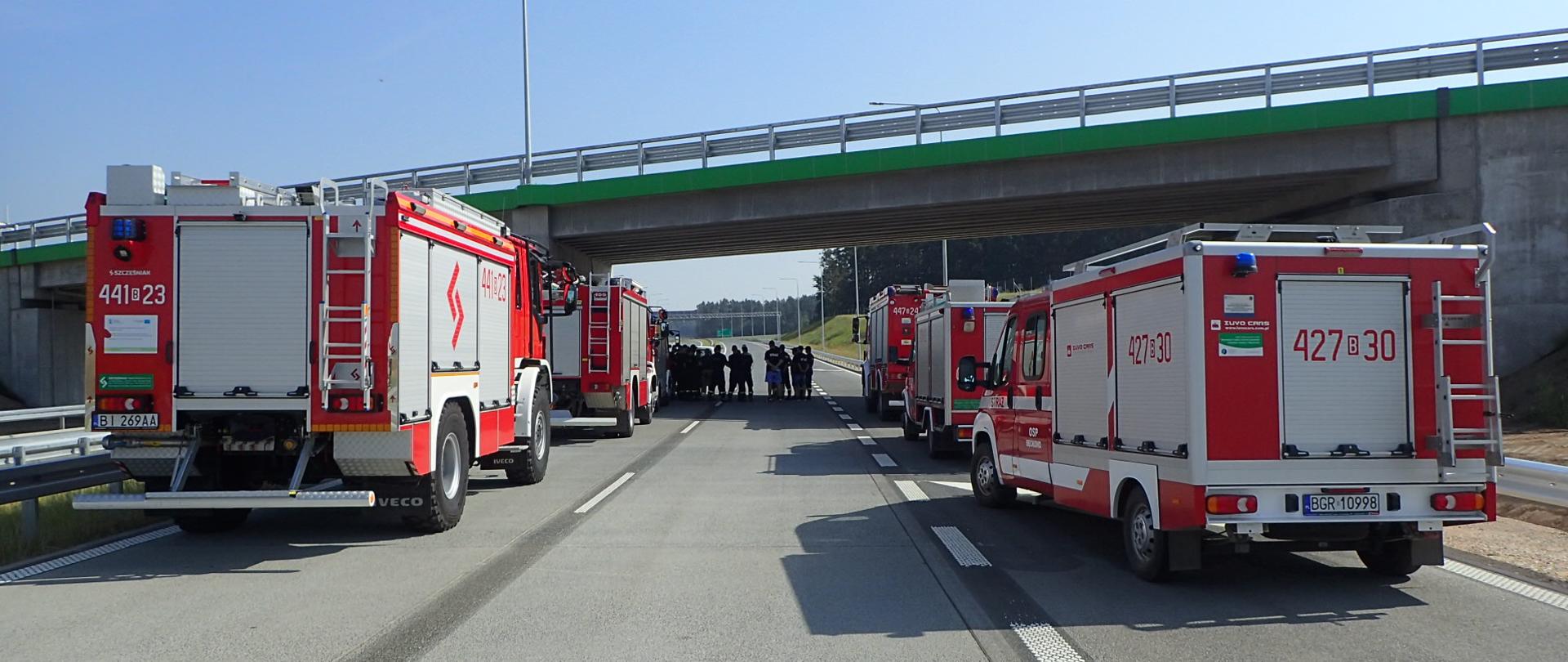 Pojazdy straży pożarnej stoją na drodze w trakcie ćwiczeń