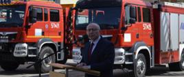Zdjęcie przedstawia Starostę Wałeckiego przy mównicy na tle samochodów pożarniczych 