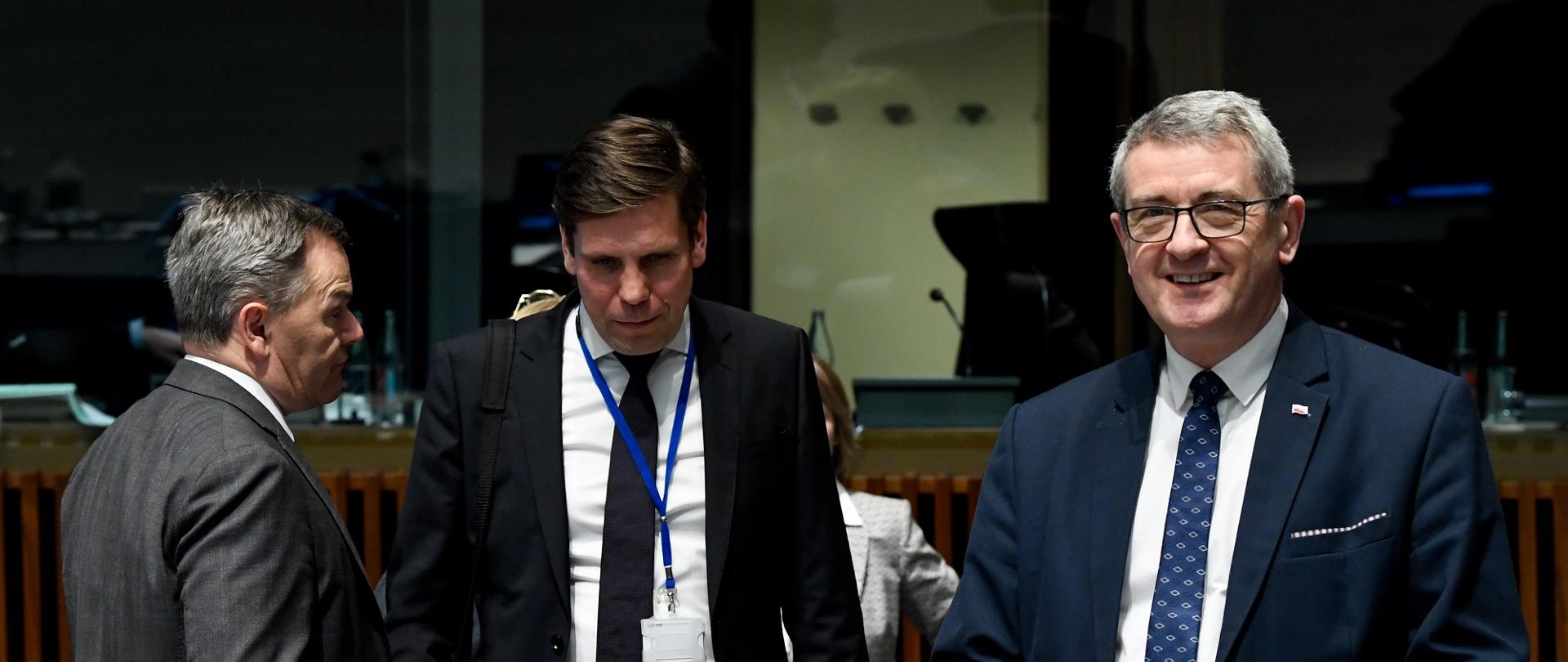 Uśmiechnięty minister Murdzek stoi na sali, obok kilku ministrów z innych krajów.