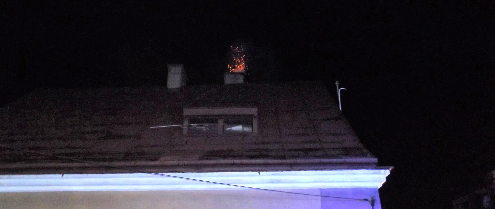 Zdjęcie przedstawia budynek mieszkalny, w którym doszło do zapalenia się sadzy w przewodzie kominowym. Widać iskry sypiące się z komina.