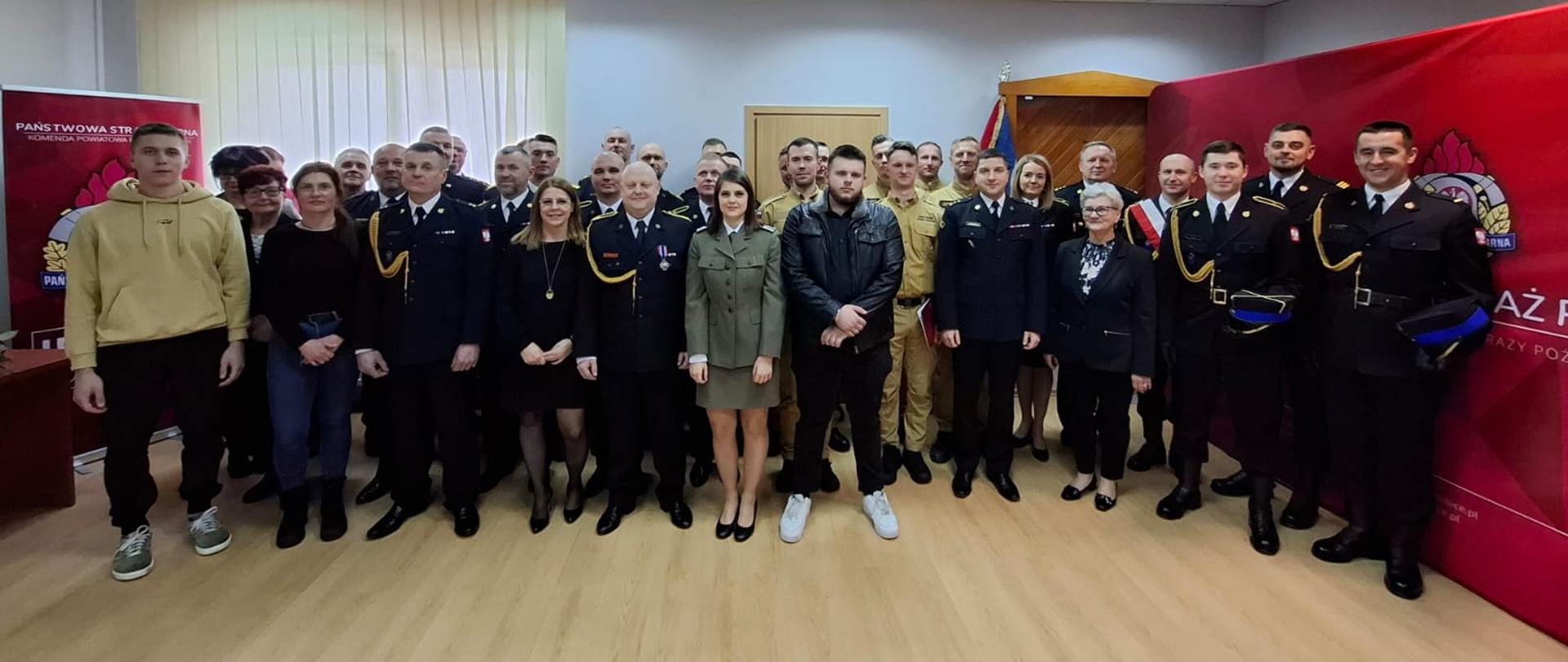 Strażacy i rodzina stoją w grupie po uroczystości