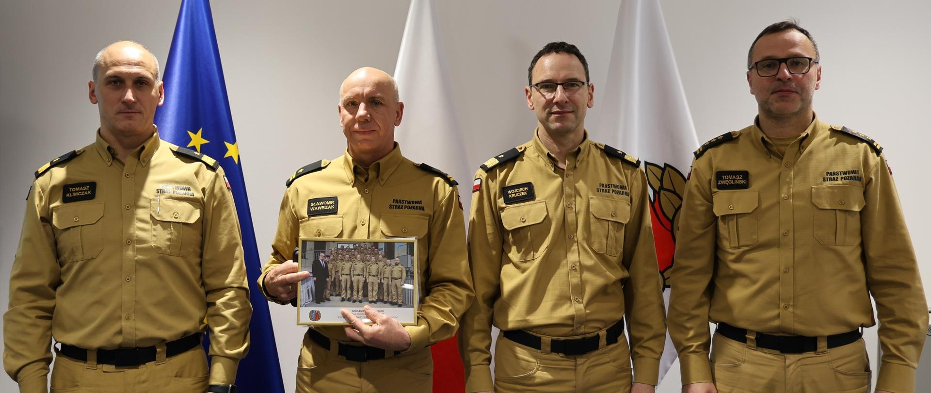 Zdjęcie przedstawia absolwenta szkolenia czyli Komendanta Powiatowego PSP w Skarżysku-Kamiennej wraz z nim do zdjęcia pozują (od lewej) Rektor Akademii Pożarniczej, Komendant Główny PSP, Prorektor Akademii Pożarniczej