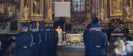Zdjęcie przedstawia ks. prałat Mieczysława Rusina, kapelana strażaków Archidiecezji Przemyskiej oraz kompanię honorową Komendy Miejskiej Państwowej Straży Pożarnej w Przemyślu, w tle poczet sztandarowy KM PSP w Przemyślu podczas Mszy Święte w Bazylice Archikatedralnej