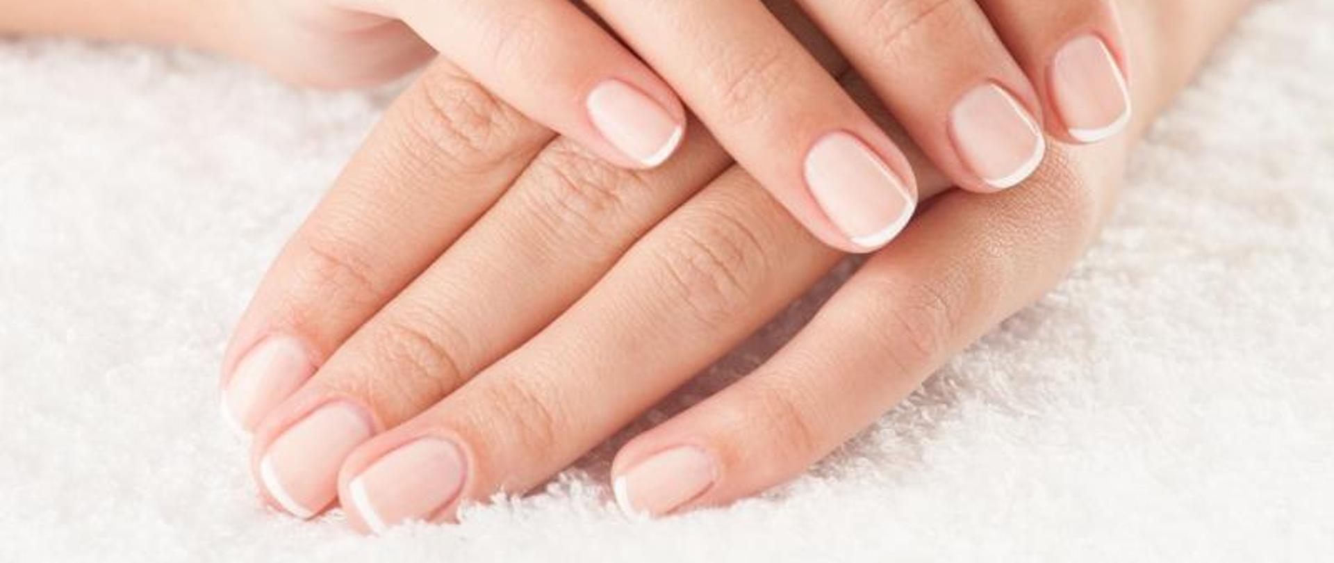 na zdjęciu widoczne dłonie bardzo zadbane, paznokcie nie umalowane. Dłonie leża na białej, puszystej tkanienie