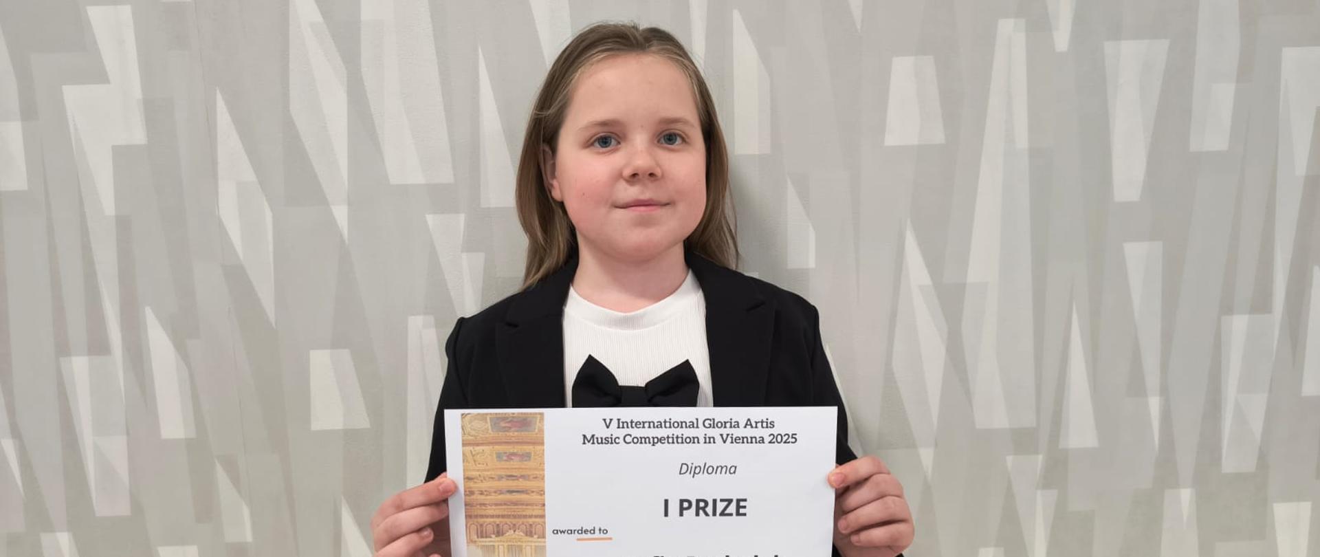 Uczennica z dyplomem na tle ściany