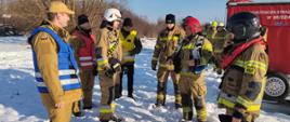 Na zdjęciu widać strażaków rozdzielających zadania do wykonania podczas części praktycznej ćwiczeń.